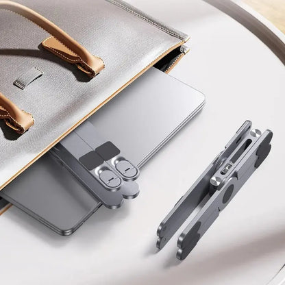 Folded UPRGHT Pivot Pro laptop stand next to a laptop sliding into a bag, showing how compact it packs for travel