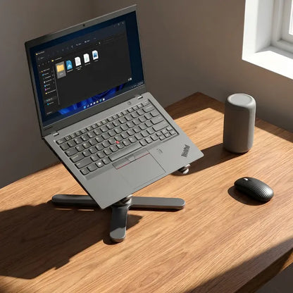 Laptop raised to eye level on the UPRGHT Pivot Pro stand on a sunlit wooden desk, next to a speaker and wireless mouse